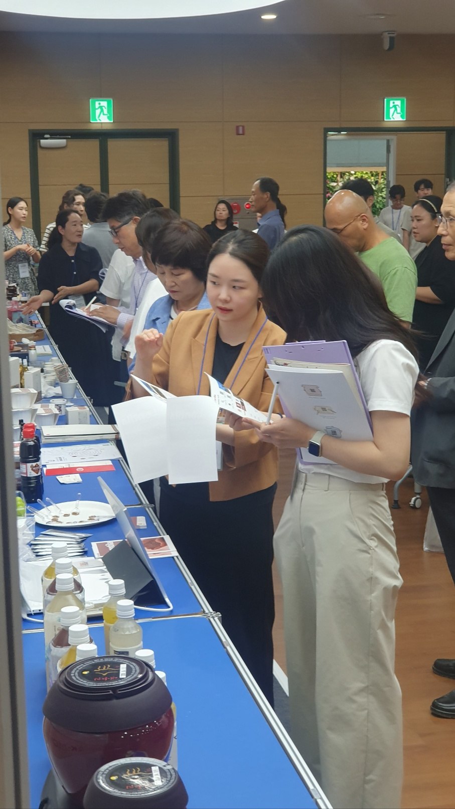 People reading about Lentila at a tasting table.